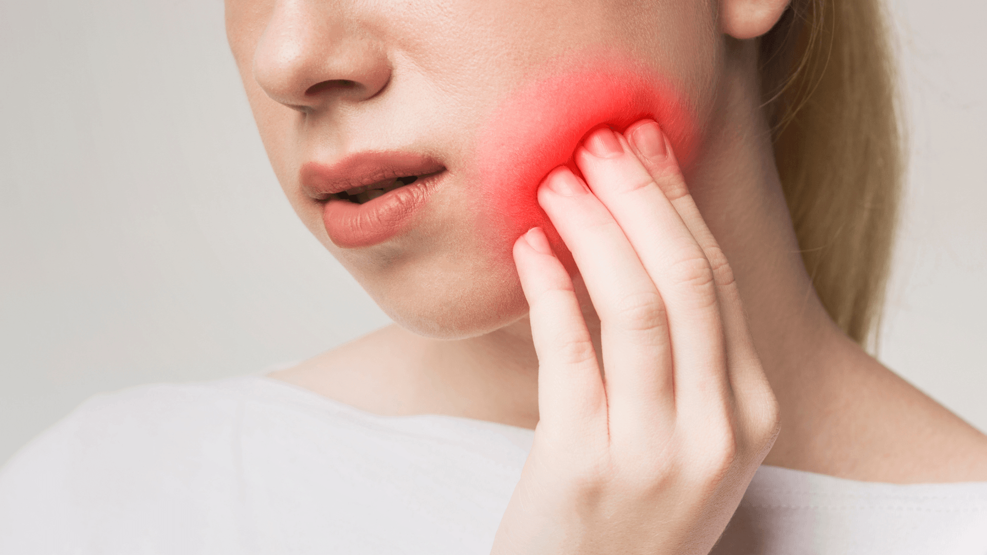 Mujer con dolor de muelas sujetándose la mejilla antes de acudir al dentista en Mérida